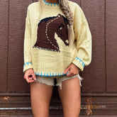 Person wearing a light-colored sweater with a horse design